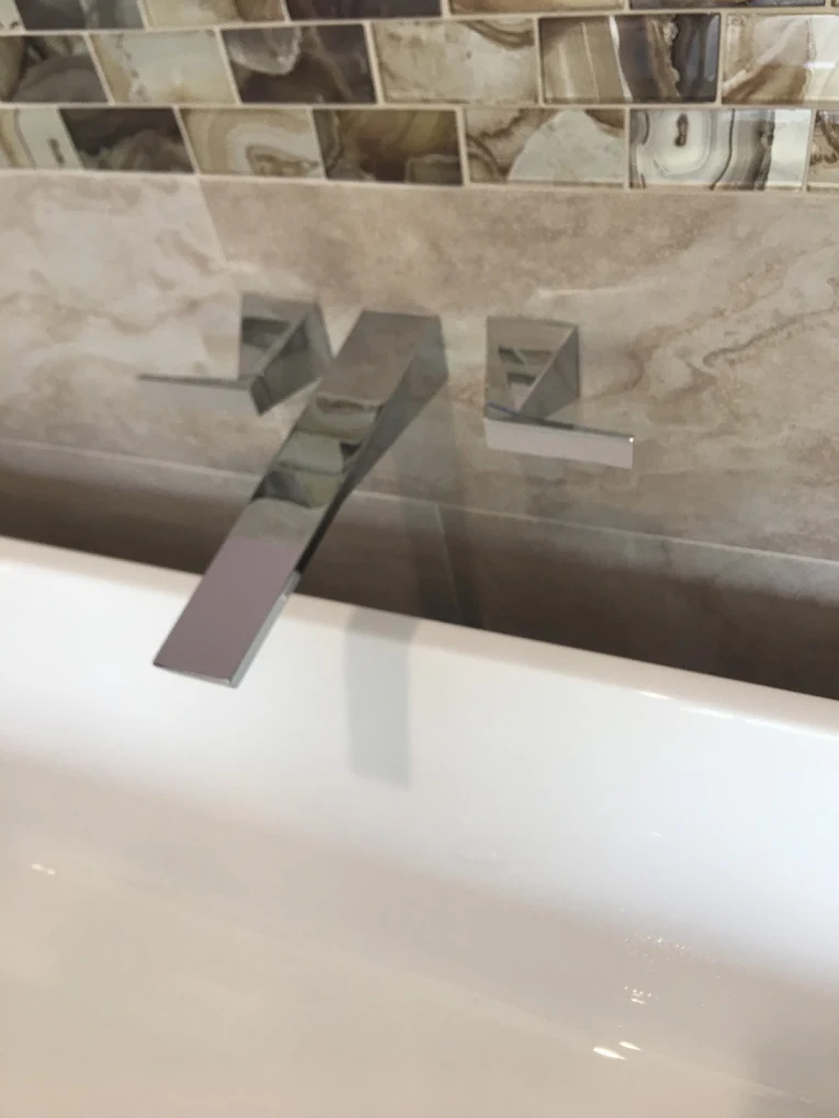 Wall-mounted tub filler and trim on stone tile