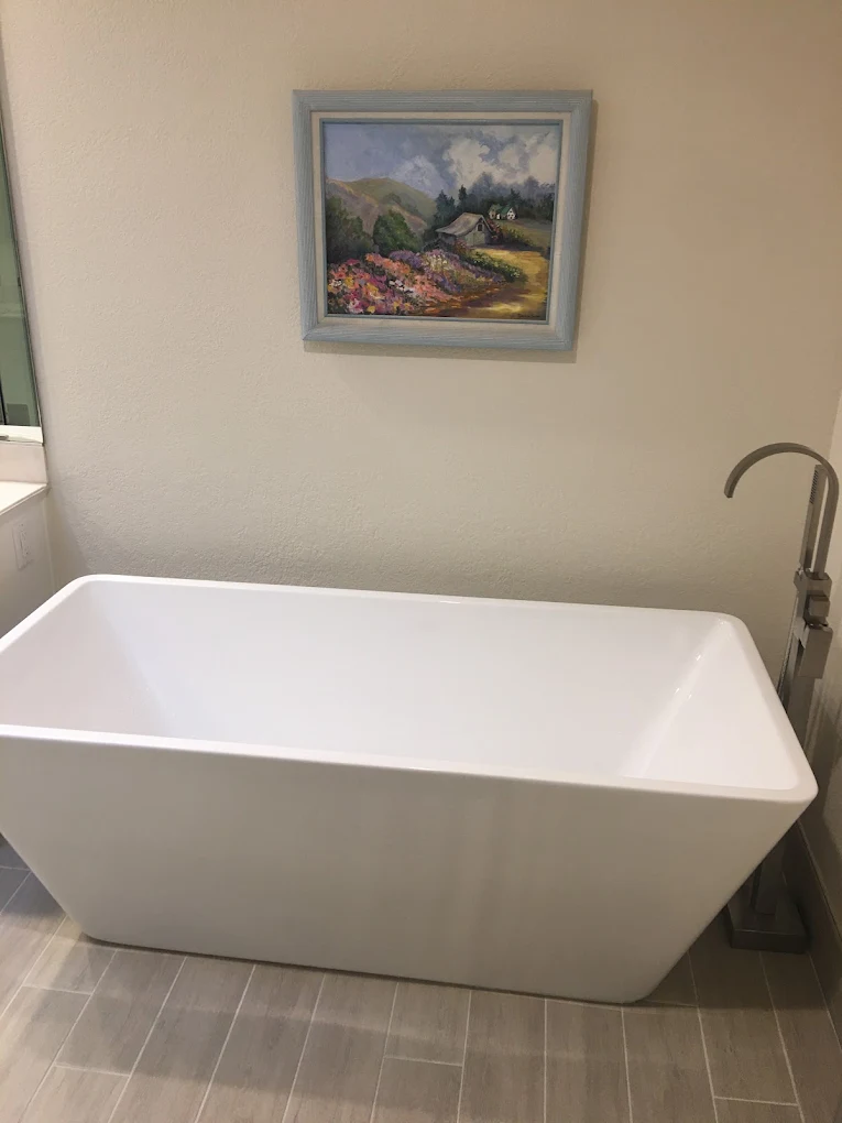 Freestanding tub against a plain wall with a slim chrome floor-mount filler
