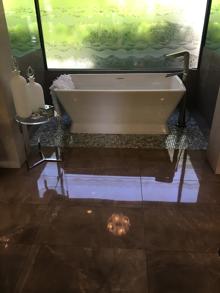 Rectangular freestanding tub on a mosaic tile plinth with a floor-mount filler