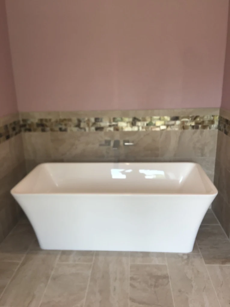 Freestanding tub set against travertine tile with a wall-mounted filler