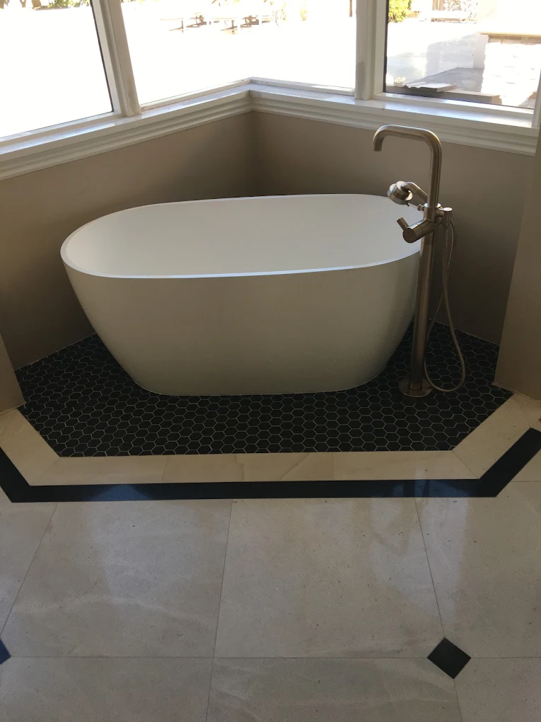 Oval freestanding tub on black hex tile with a floor-mount filler